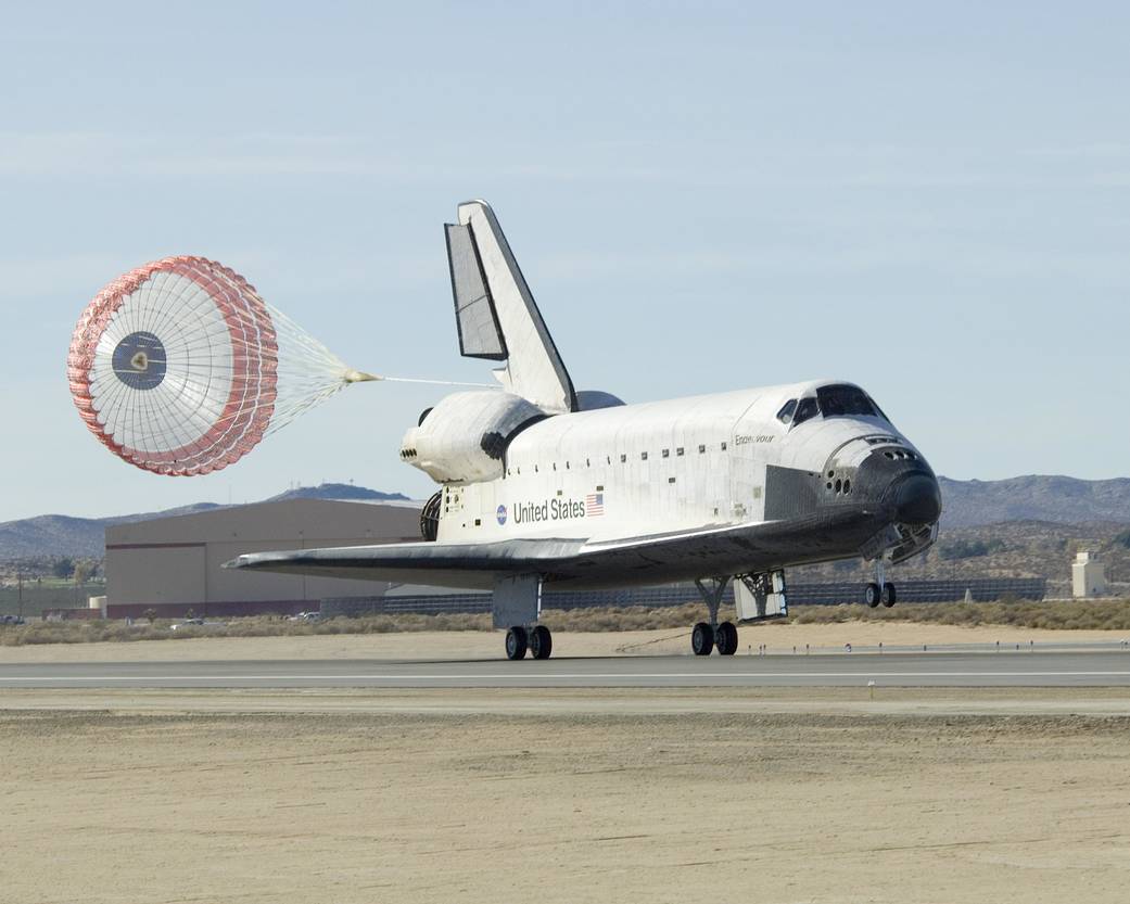 Shuttle Endeavour touches down on runway with parachute behind
