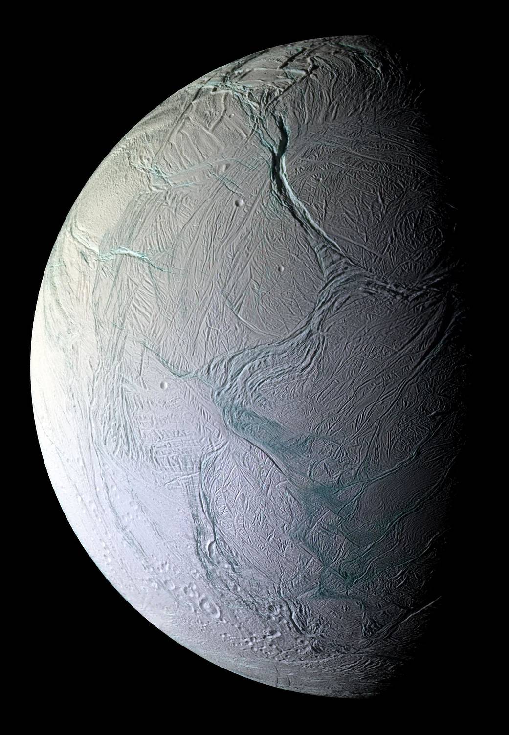 View in black and whilte of half of the moon Enceladus as the other half recedes into shadow