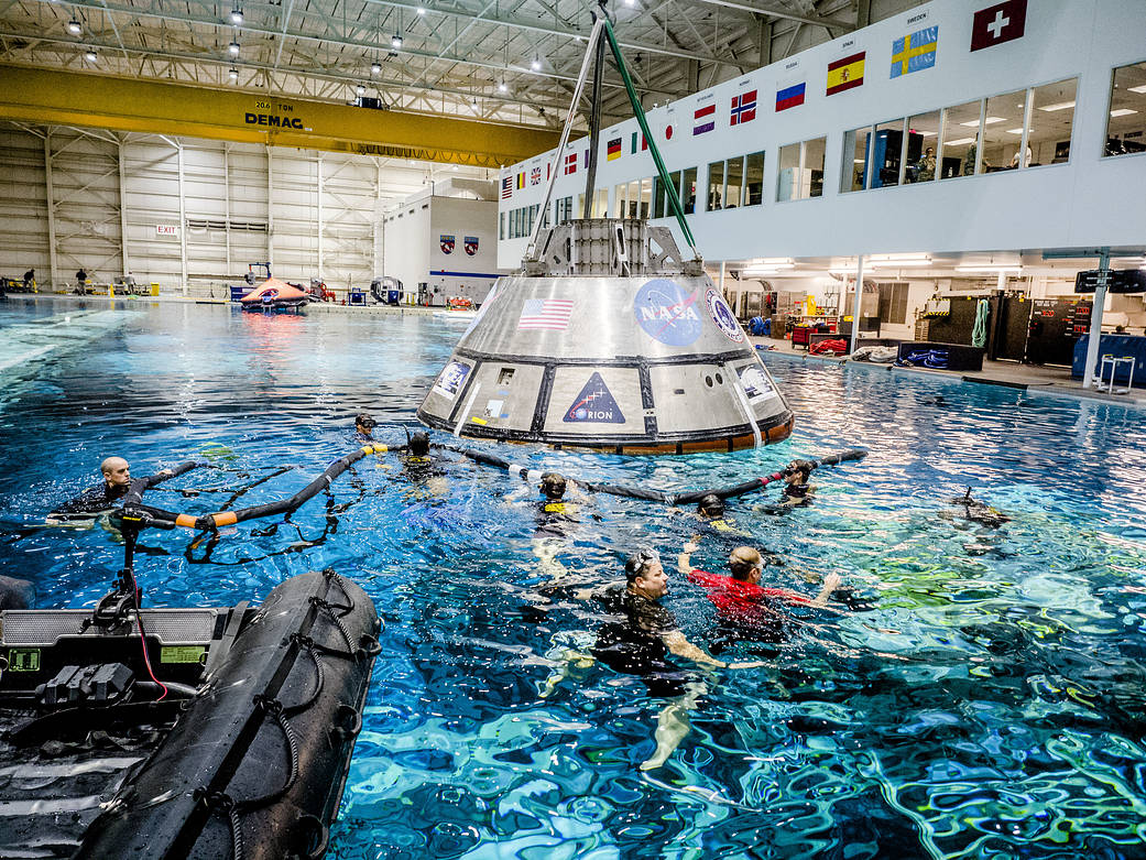 Orion spacecraft in large pool with divers