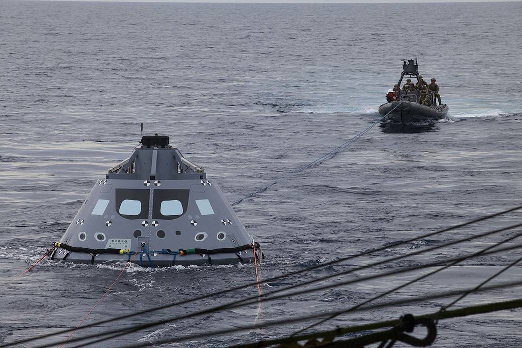 Orion crew module test article in ocean attached with tether to boat