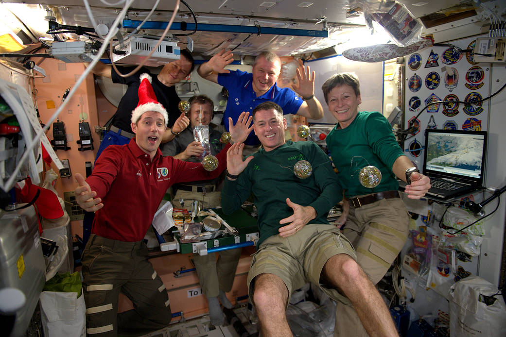 Space station crew with holiday meal and ornaments