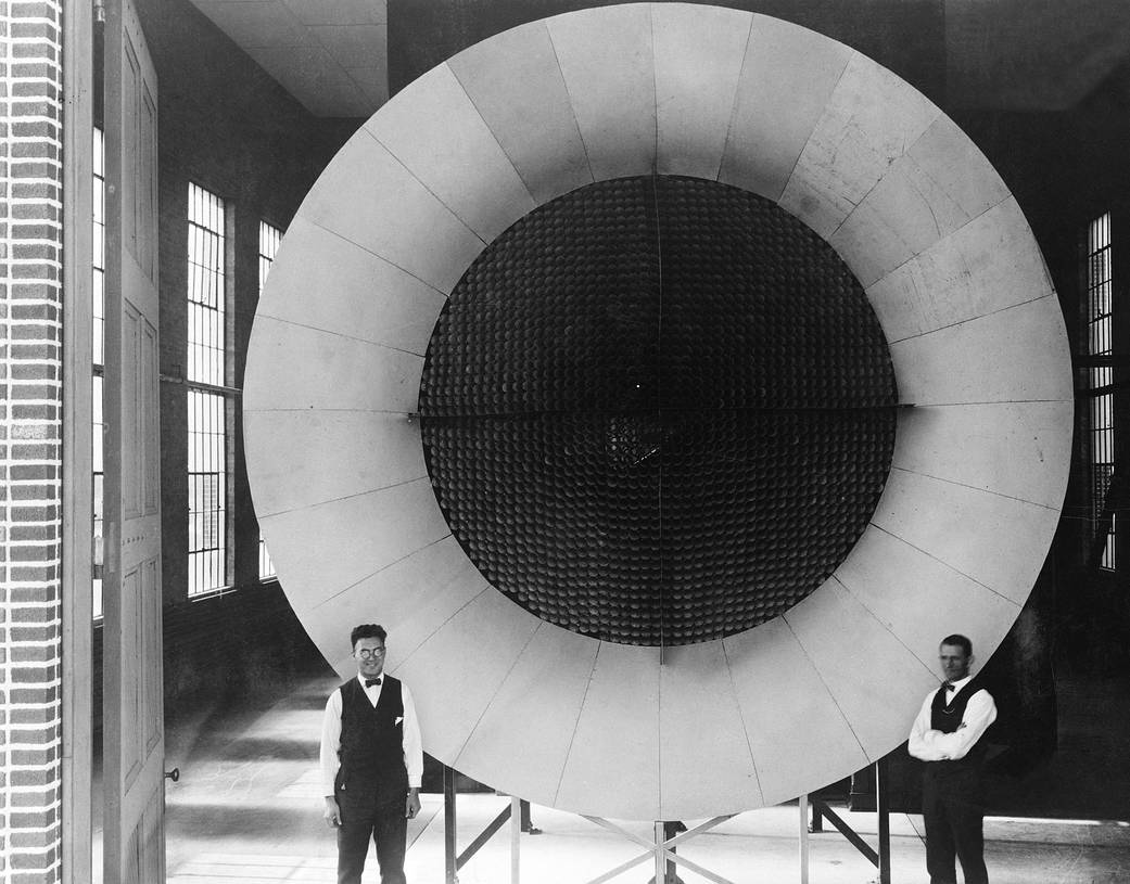 Two men stand at the end of a large circular honeycombed screen