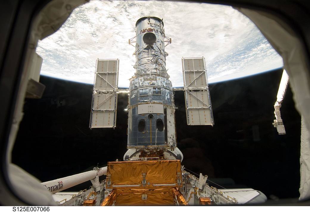 Hubble inside shuttle cargo bay with Earth in background