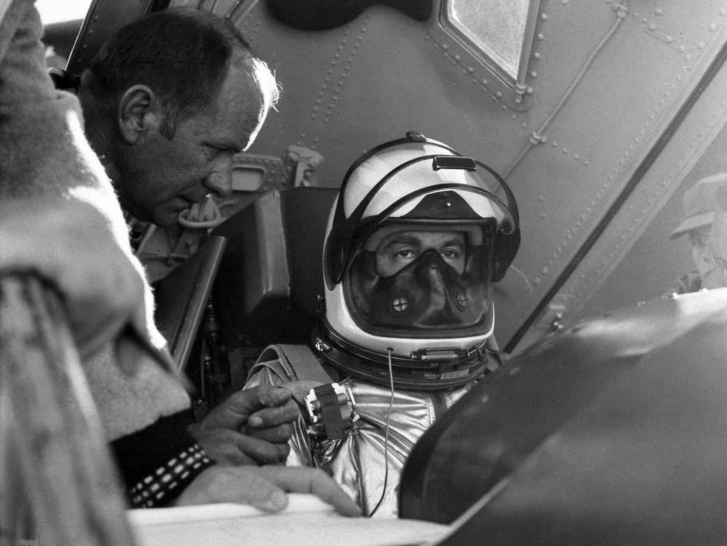 A test pilot wearing his helmet, has help from a technician get seated into the cockpit of the X-15 rocket.