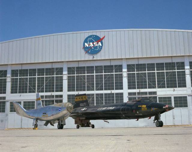 The HL-10 and X-15 sit outside the hangar at Dryden Flight Research Center