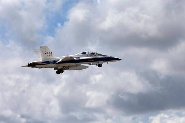 NASA F-18 jet in flight with clouds in the background.