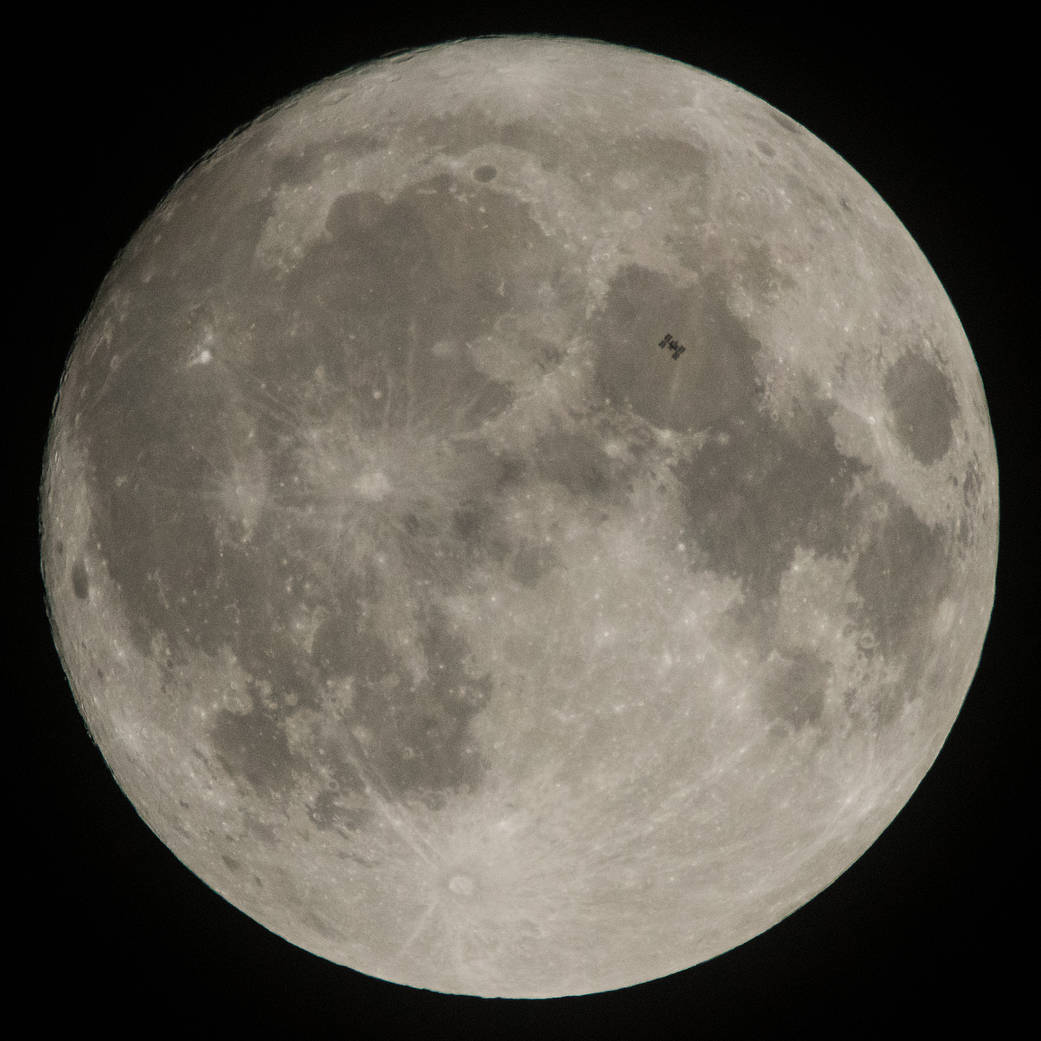 Space station seen in front of large full moon