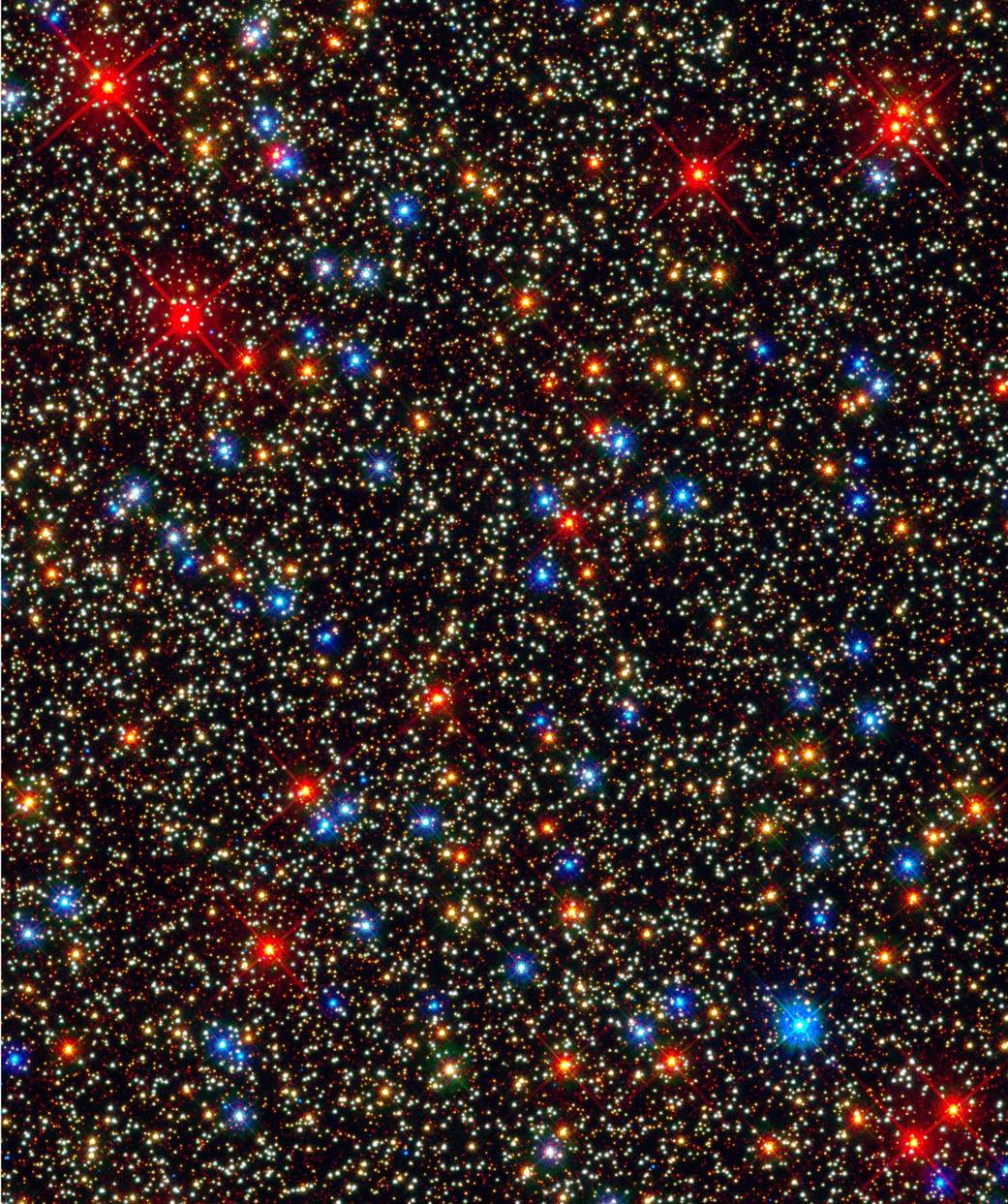 Wide field image of stars with some in white and others in bright yellow blue and red against deep space