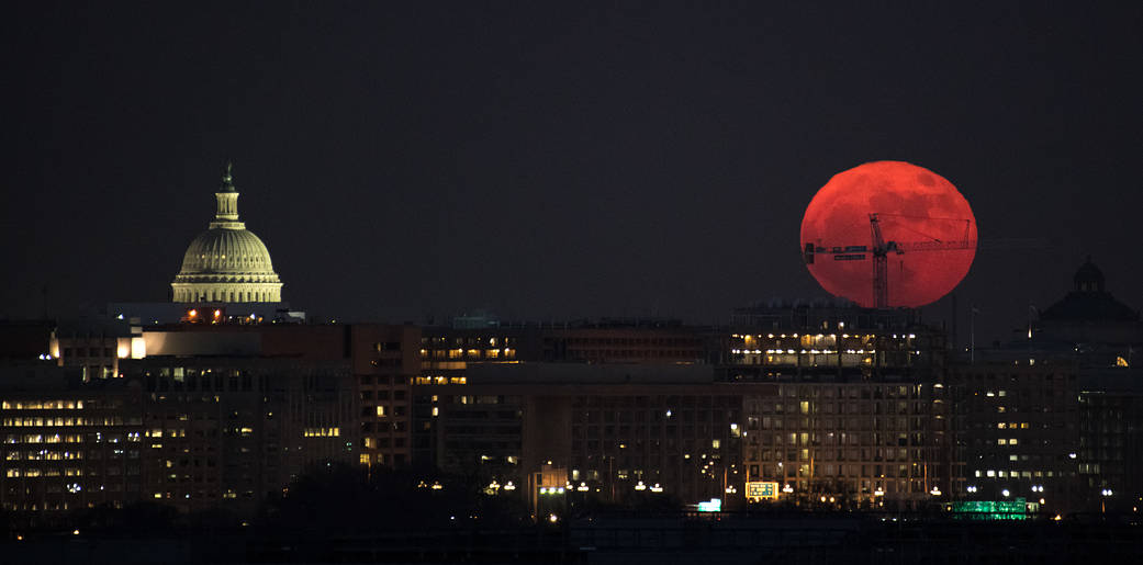 Moon rises over Washington DC, Capitol building at left of skyline