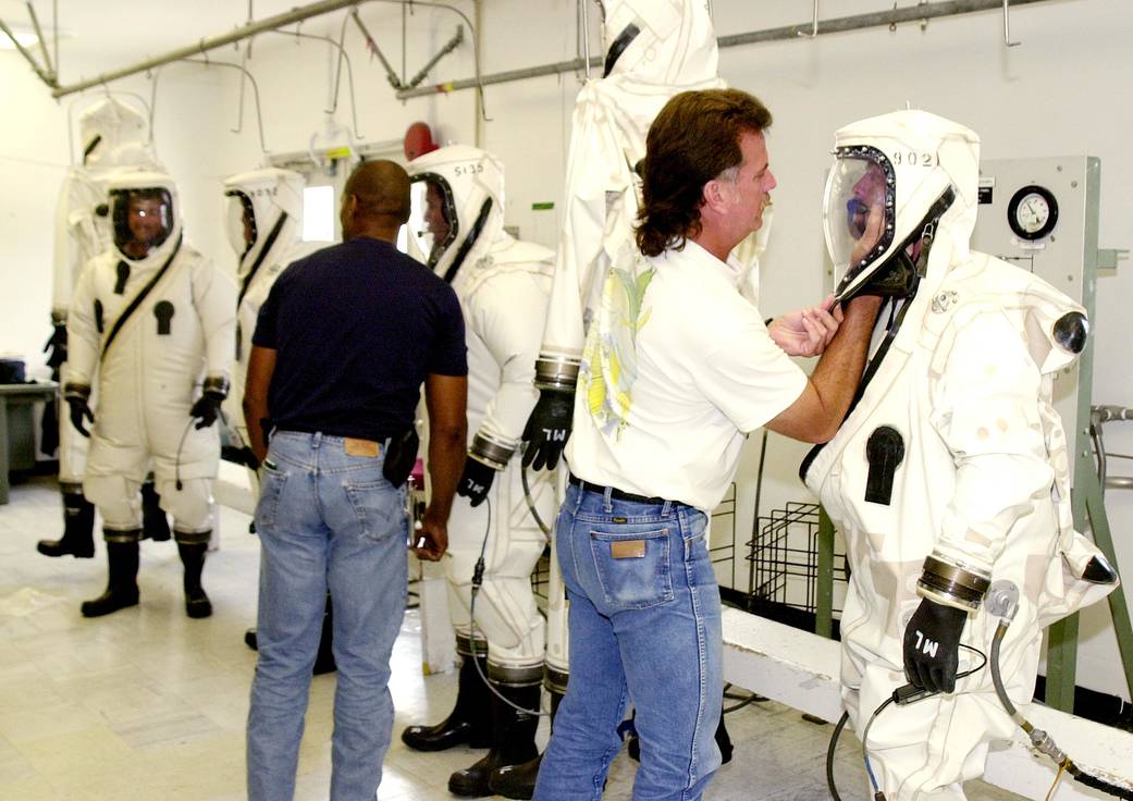 Workers finish donning SCAPE suits for the fueling of the Comet Nucleus Tour (CONTOUR) spacecraft.