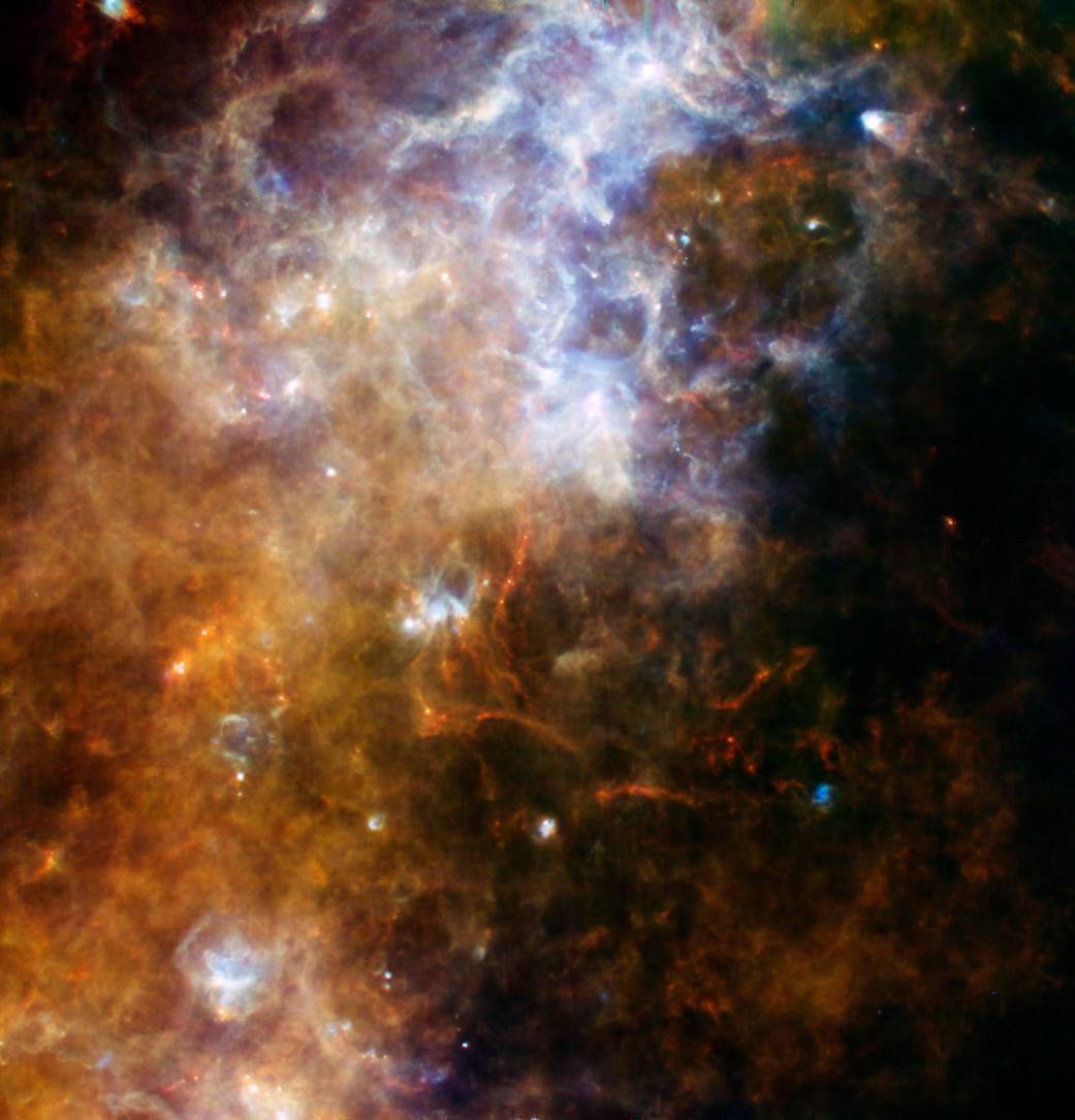 Bright cloud of gas in yellows toward bottom left and white in upper center with red throughout and bright white spots