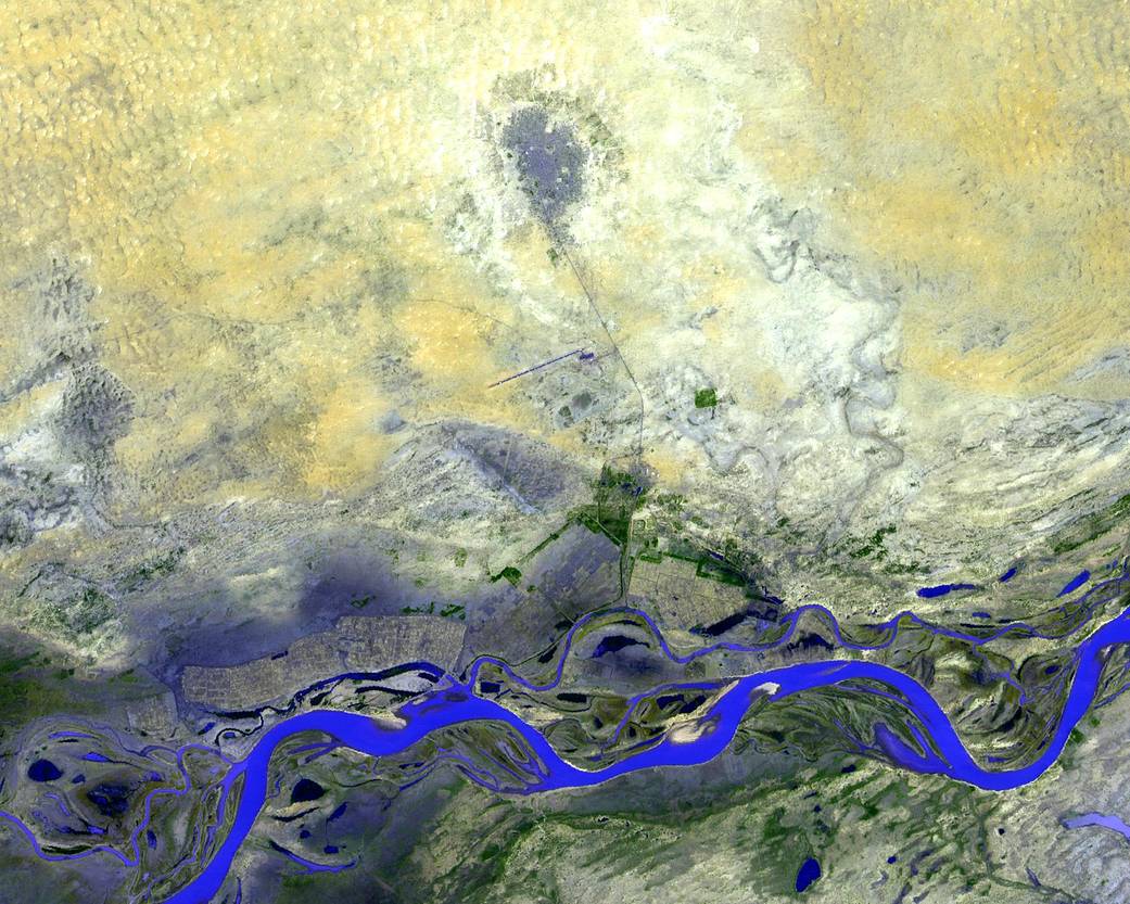 Satellite image of dry land in pale yellow with bright blue river running horizontally across the bottom