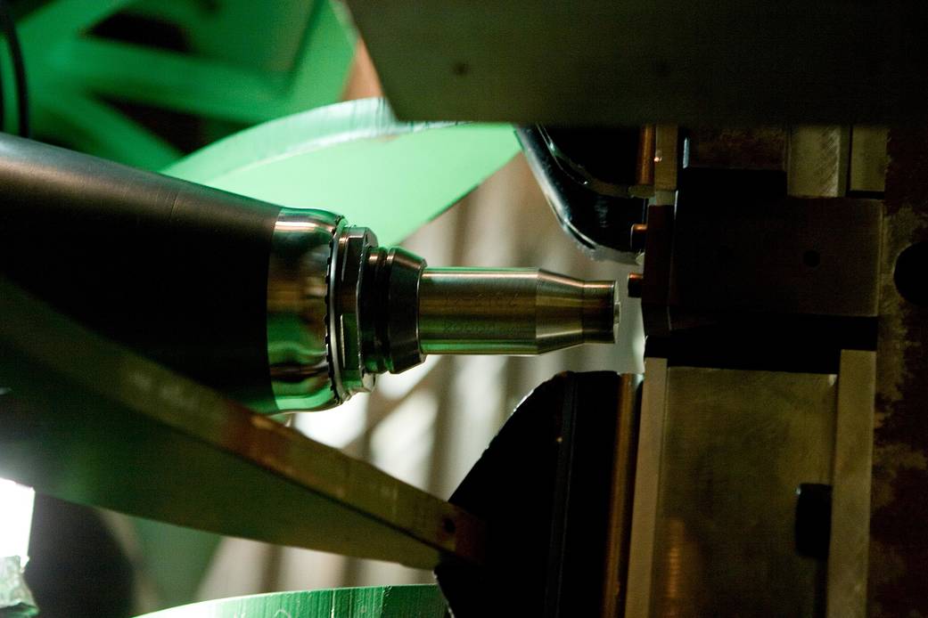 Closeup of nozzle of welding machinery with green light behind