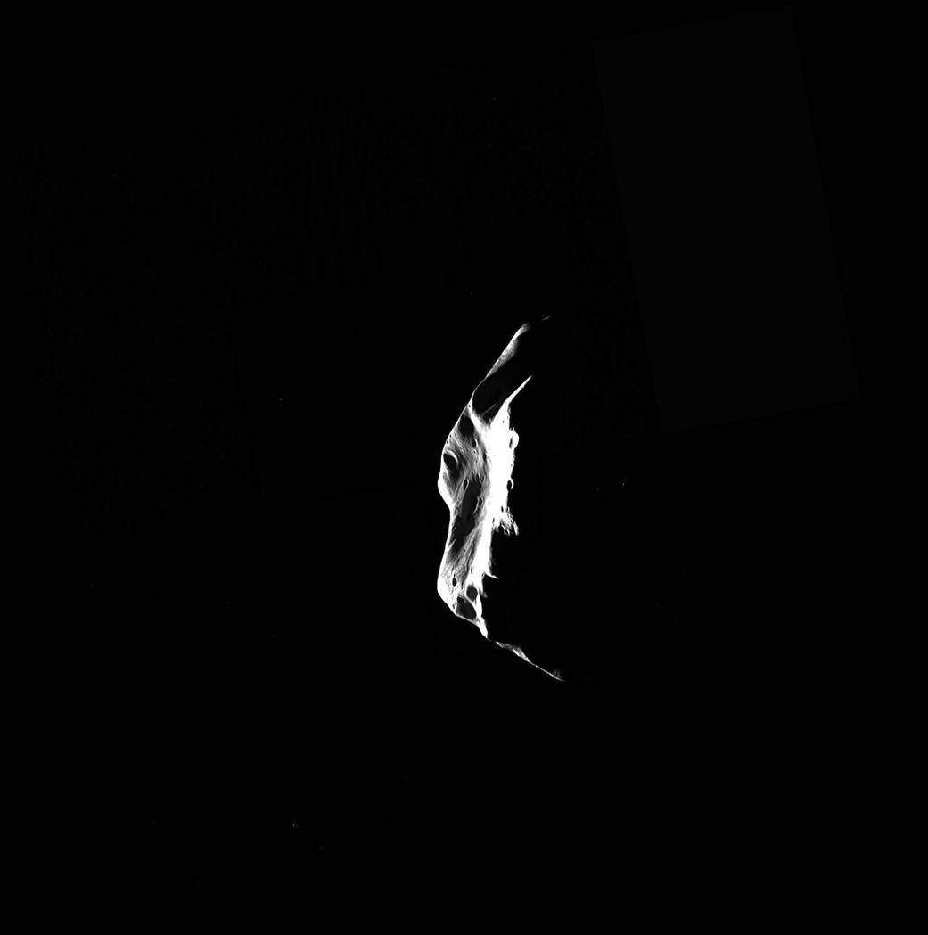 Side of irregularly shaped, cratered asteroid lit from the left against deep space