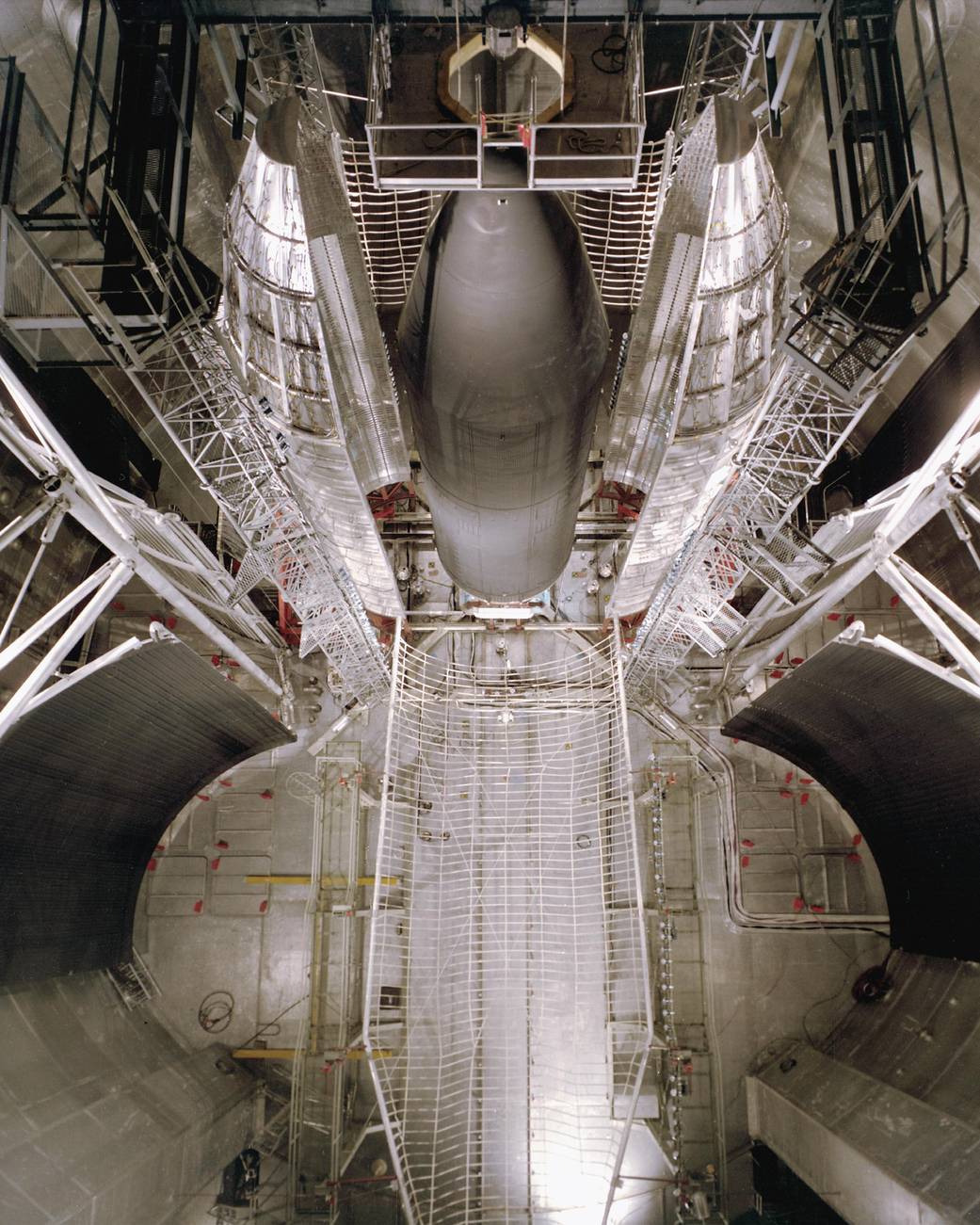 Metal shroud and scaffolds surrounding spacecraft model in large room