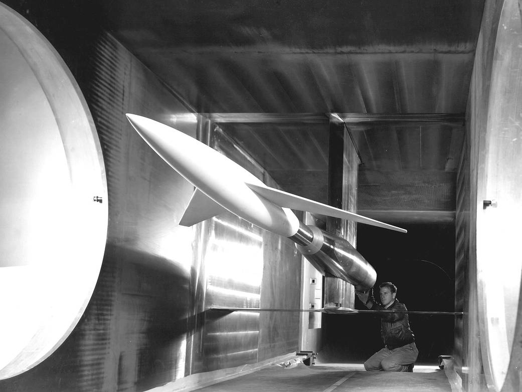 A black and white photo of an engineer making calibrations on the model inside the 6x6 foot supersonic wind tunnel.