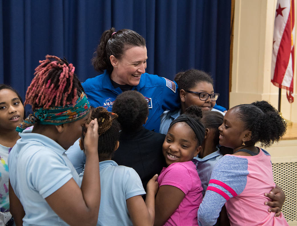 NASA astronaut Dr. Serena Auñón-Chancellor is hugged by students after a presentation about her experience on Station.