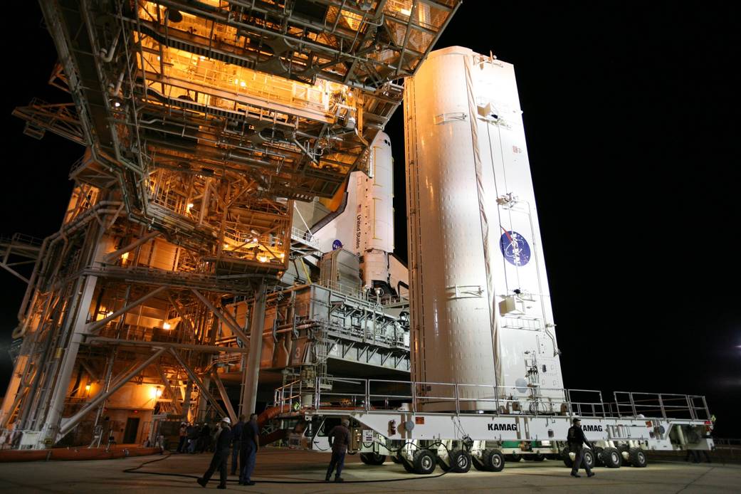 Workers monitor the arrival of the STS-133 payload canister at Launch Pad 39A where it will be lifted into the rotating service 