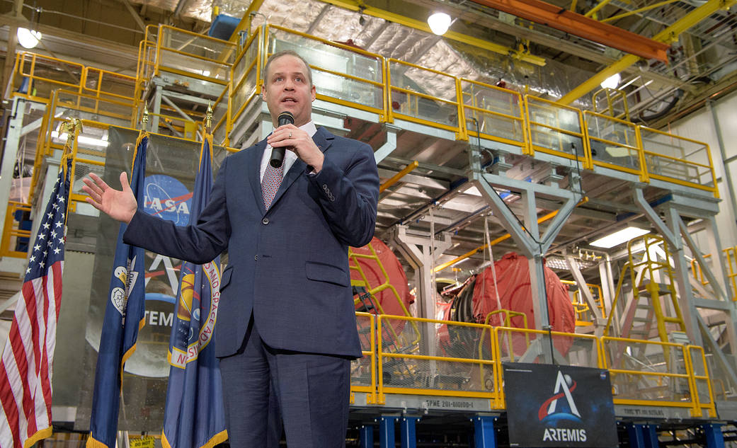 Administrator Bridenstine speaking with SLS rocket stage in background