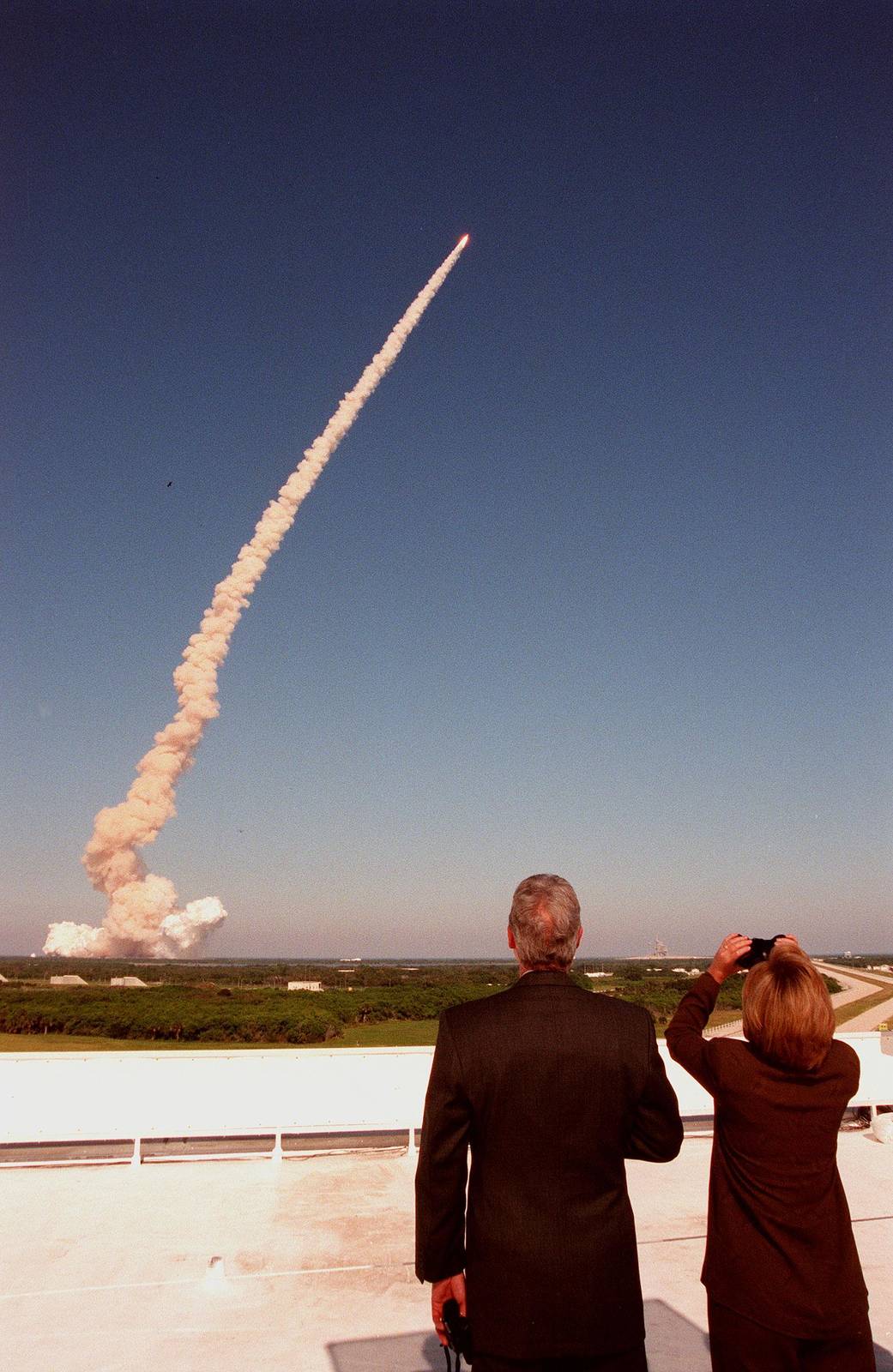 From the roof of the Launch Control Center, U.S. President Bill Clinton and First Lady Hillary Rodham Clinton track the plume and successful launch of space shuttle Discovery on mission STS-95.
