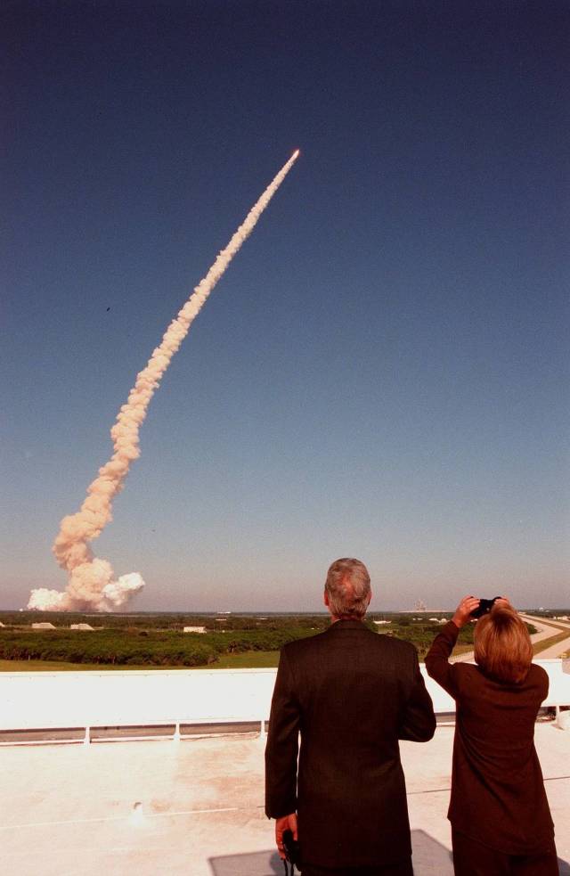 From the roof of the Launch Control Center, U.S. President Bill Clinton and First Lady Hillary Rodham Clinton track the plume and successful launch of space shuttle Discovery on mission STS-95. 