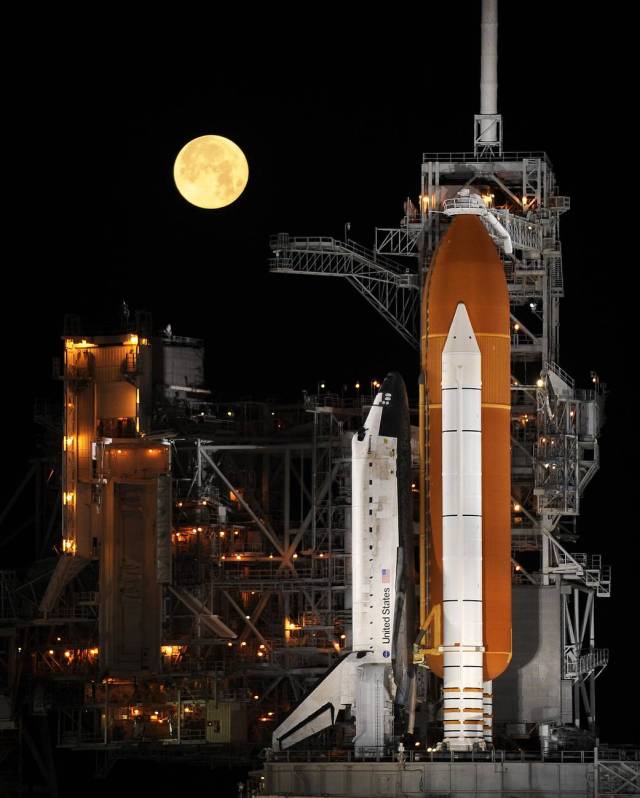 Under a full moon on Launch Pad 39A, space shuttle Discovery is revealed after the rotating service structure has been rolled back in preparation to launch on STS-119.