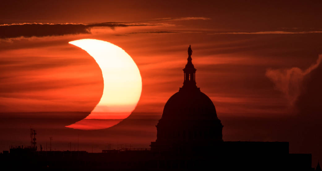 A partial solar eclipse is seen as the sun rises to the left of the United States Capitol building, Thursday, June 10, 2021, as seen from Arlington, Virginia. The annular or “ring of fire” solar eclipse was visible in the far northern hemisphere. 