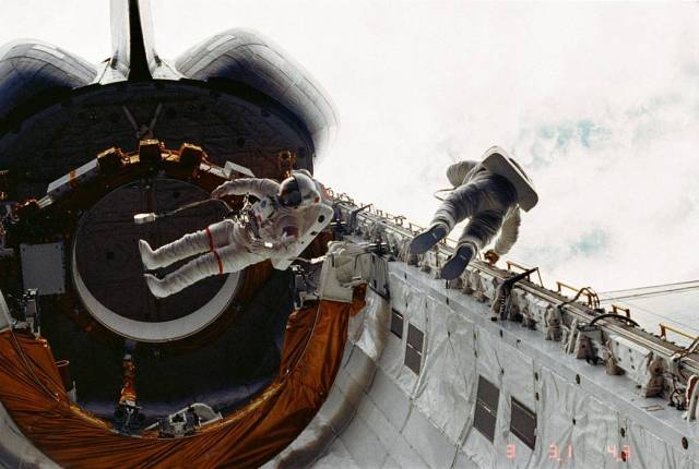 Astronauts on tethered spacewalk in cargo bay of space shuttle