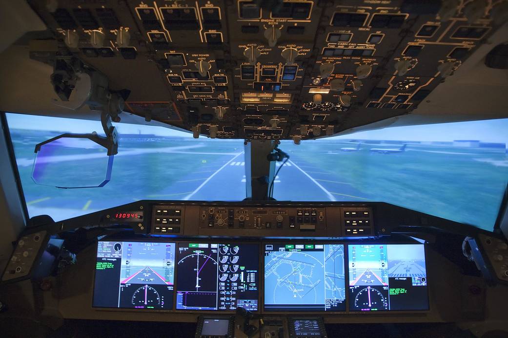 View from inside cockpit of aircraft with instrument panels surrounding and runway ahead.