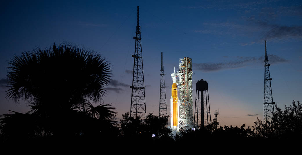 NASA’s Space Launch System (SLS) rocket with the Orion spacecraft aboard is seen illuminated by spotlights after sunset atop the mobile launcher at Launch Pad 39B
