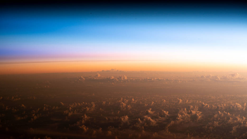 The soft hues of an orbital sunrise begin revealing the cloud tops above the Pacific Ocean northeast of New Zealand as the International Space Station orbited 260 miles above.