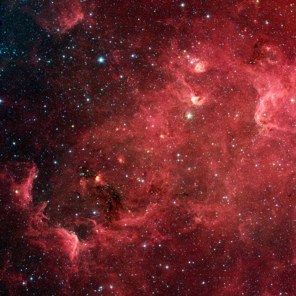 Bright cloud of dust and gas in shades of deep red with brighter reds at upper right and stars throughout