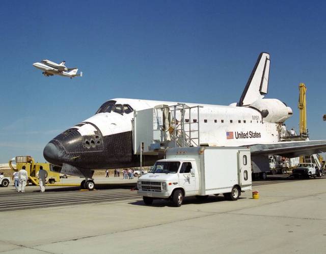 Shortly after landing at Edwards Air Force Base in California, at the completion of STS-68, the space shuttle Endeavour receives a high-flying salute from shuttle Columbia atop NASA's Shuttle Carrier Aircraft.