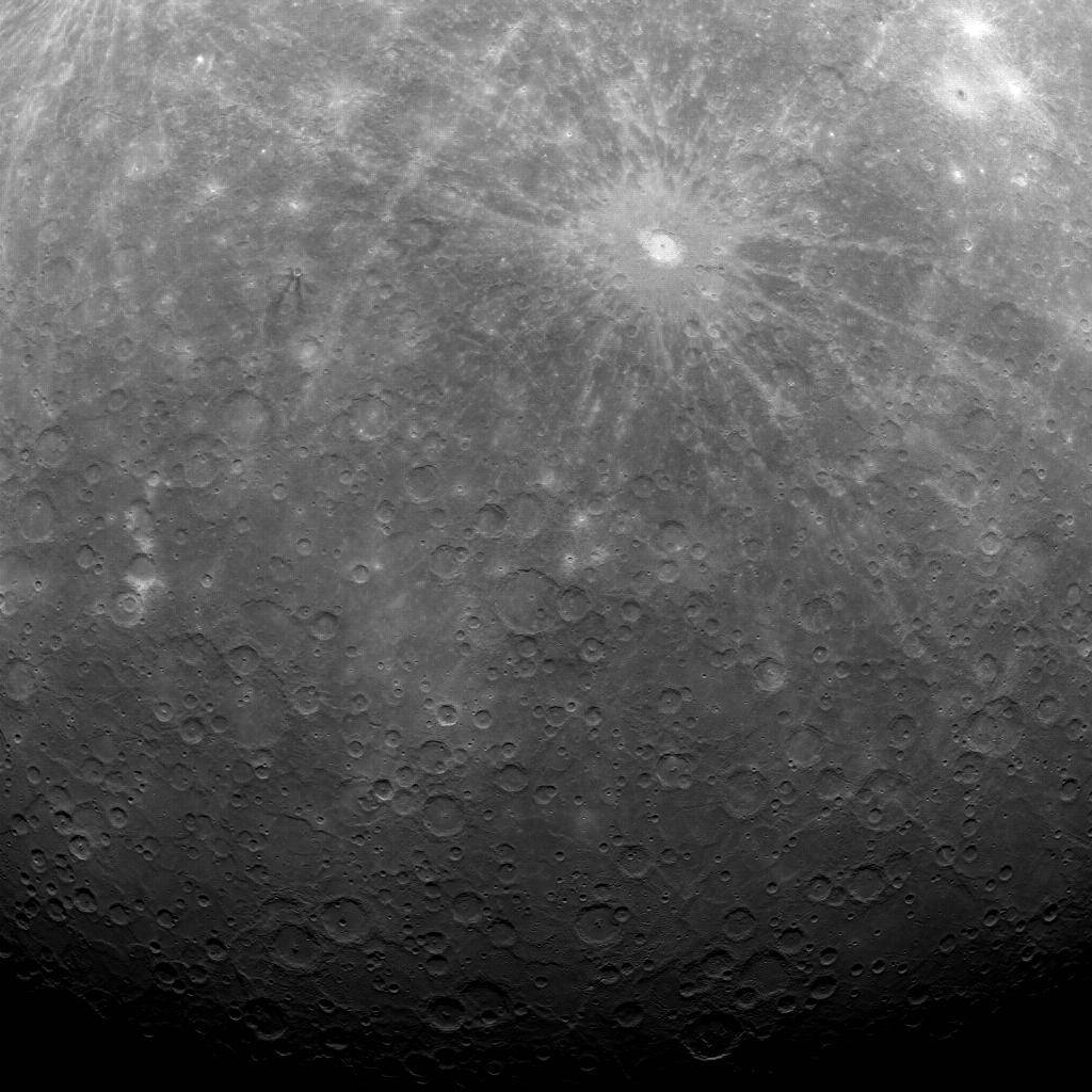 Cratered surface of Mercury from above with bright white crater at upper right and shadow toward bottom