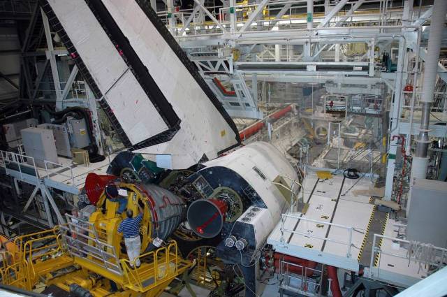 In Orbiter Processing Facility-3, technicians on a Hyster forklift maneuver a 14-foot-long, 6,700-pound space shuttle main engine into place on Endeavour during prelaunch preparations for mission STS-123.