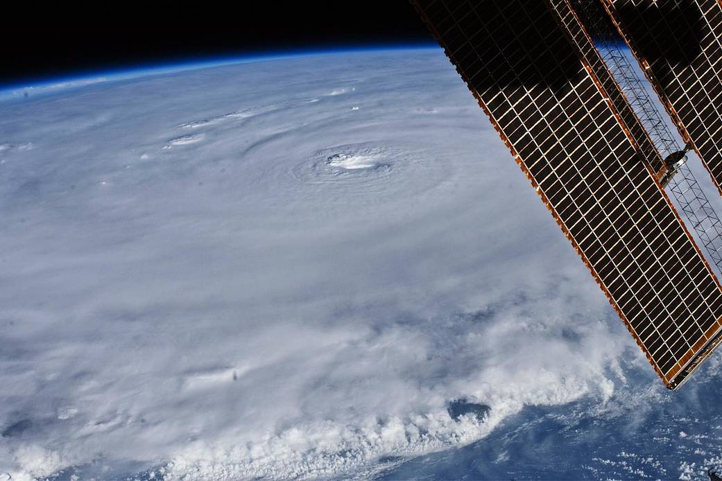 Large hurricane viewed from orbit with space station solar array at left of frame