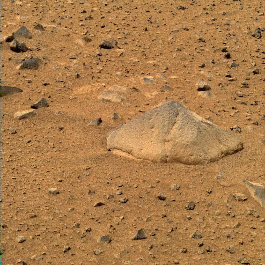 Closeup of Mars surface showing large rock and smaller rocks on flat terrain