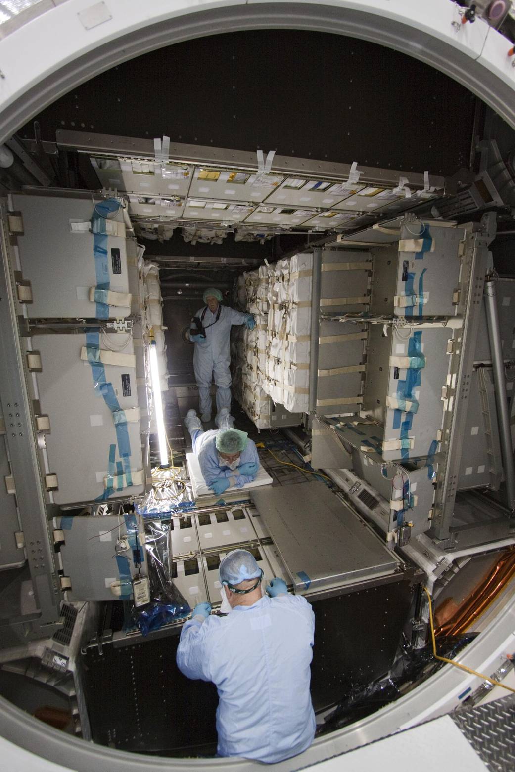 Technicians install cargo inside the Raffaello multi-purpose logistics module in preparation for the STS-135 mission.