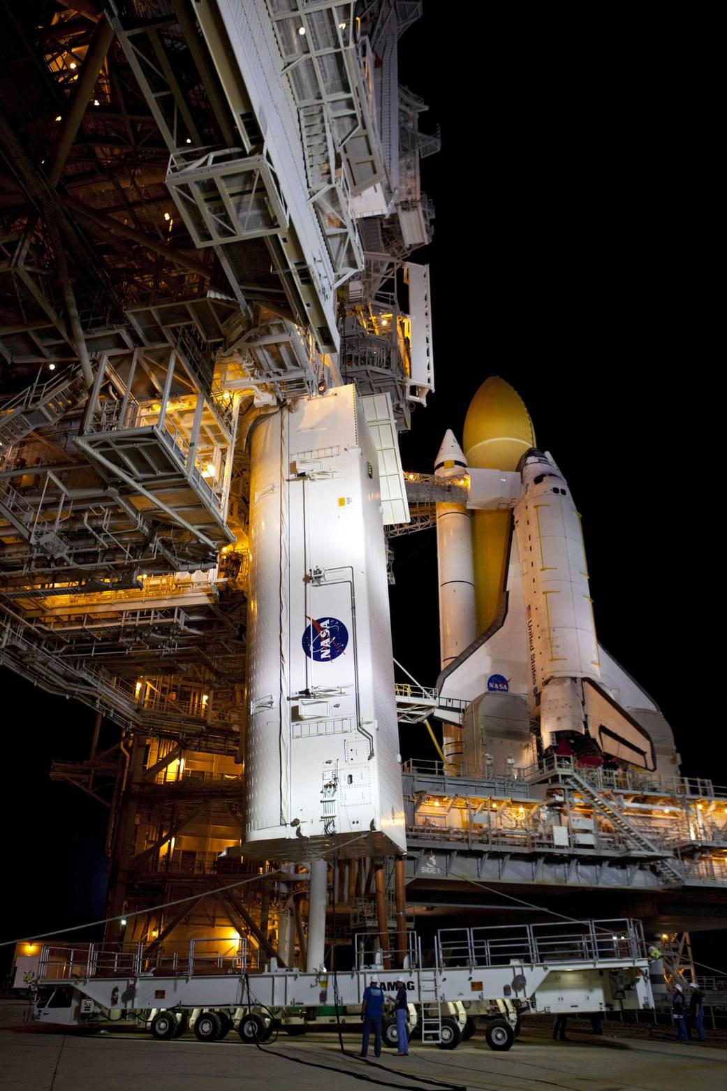 The transportation canister carrying the STS-135 payload is lifted toward the payload changeout room on Launch Pad 39A's rotatin