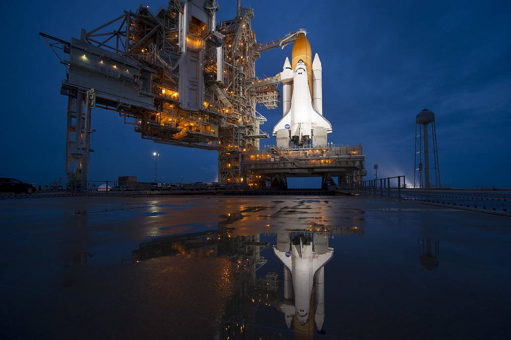 Shuttle Atlantis at launch pad with reflection in water visible