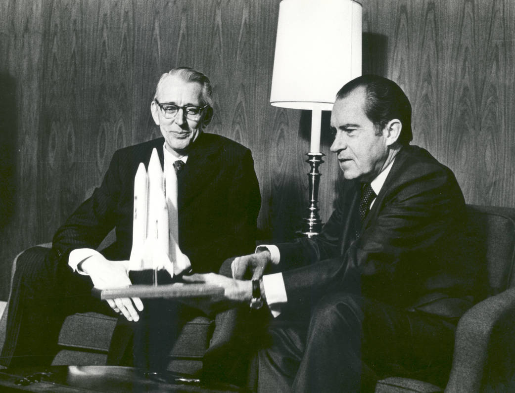Richard M. Nixon and James C. Fletcher sit together with a model of the Space Shuttle.