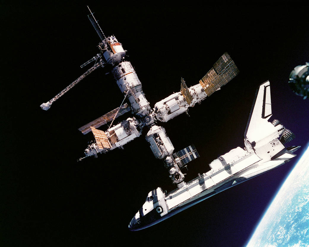 Space shuttle docked in orbit with Russian space station Mir with Earth below