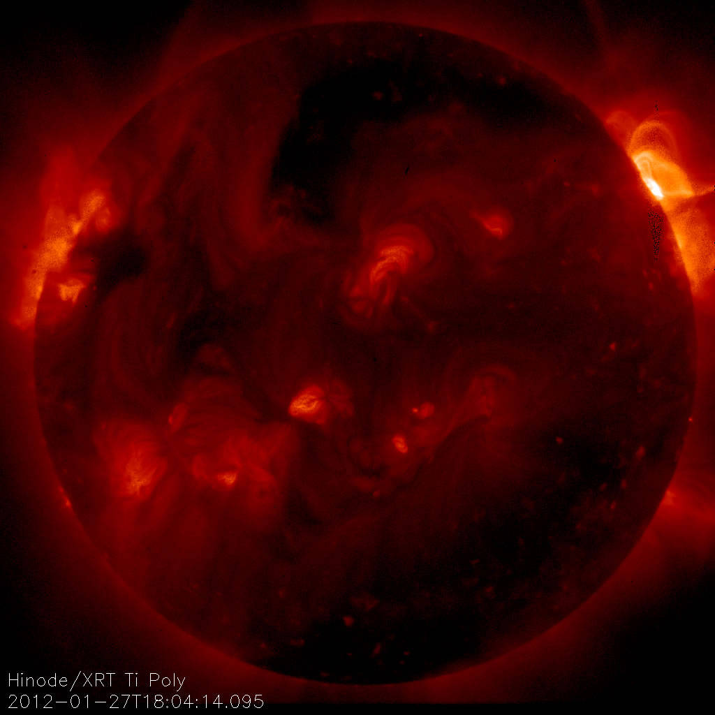 Large full disc image of the Sun in deep red and orange with flare erupting at upper left