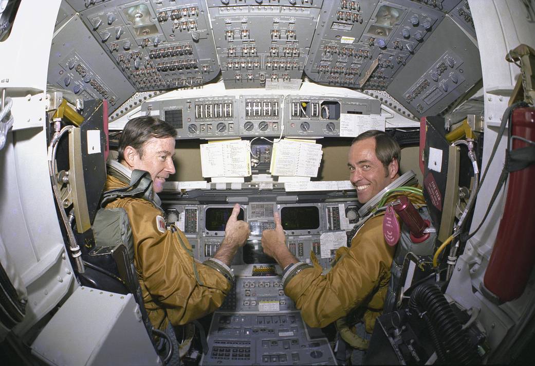 Astronauts for the first space shuttle mission, Commander John Young and Pilot Robert Crippen, take a break from their intensive training schedule to pose for pictures in the flight deck of the shuttle Columbia.