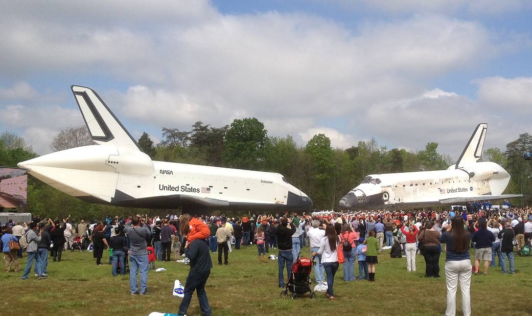 Shuttle Enterprise and shuttle Discovery nose to nose on green lawn outside Udvar-Hazy Center of Air and Space Museum