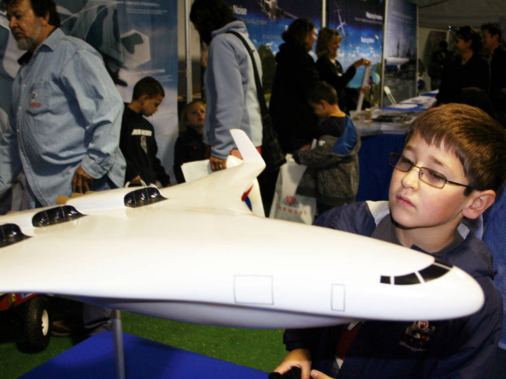 A young child looking at the blended wing body aircraft model.