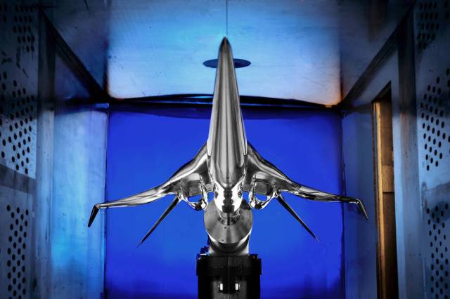 Symmetrical front view of silver aircraft model in blue wind tunnel