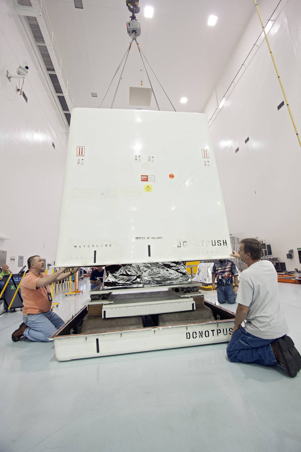 Technicians finish lowering the cover of a shipping container that will enclose the orbital replacement unit for the space stati