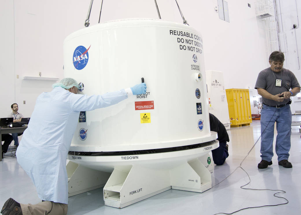 Technicians install the cover of the shipping container enclosing the Space Test Program-Houston 4 experiment.