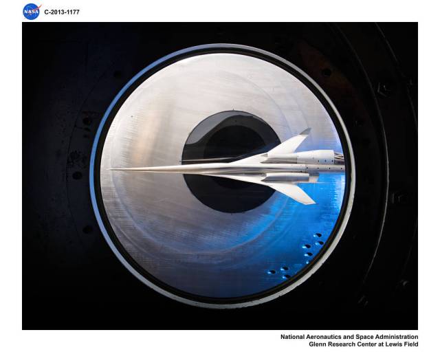 A view from a window looking into the 8- by 6-foot supersonic wind tunnel viewing a model of the future concept supersonic aircraft model.